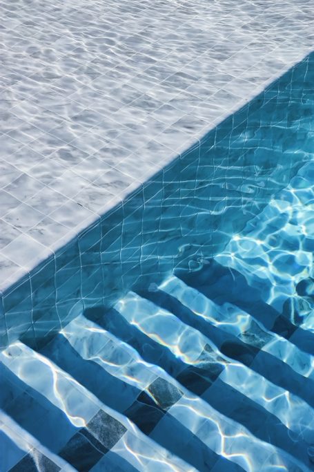 Light ripples on a swimming pool's surface with visible striped steps.